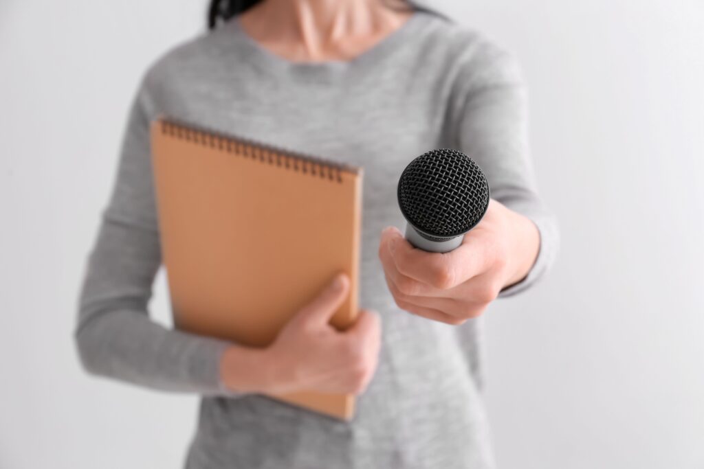 woman giving microphone and holding a notebook