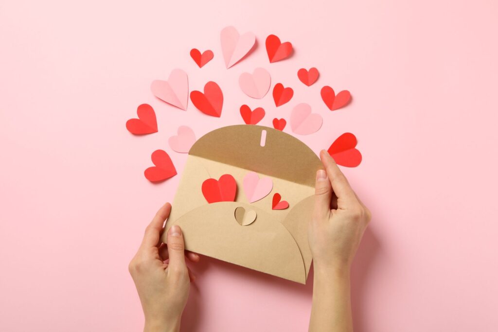 A woman's hand opening a letter with hearts, symbolizing self-love, positivity, and the power of writing a letter to your future self.