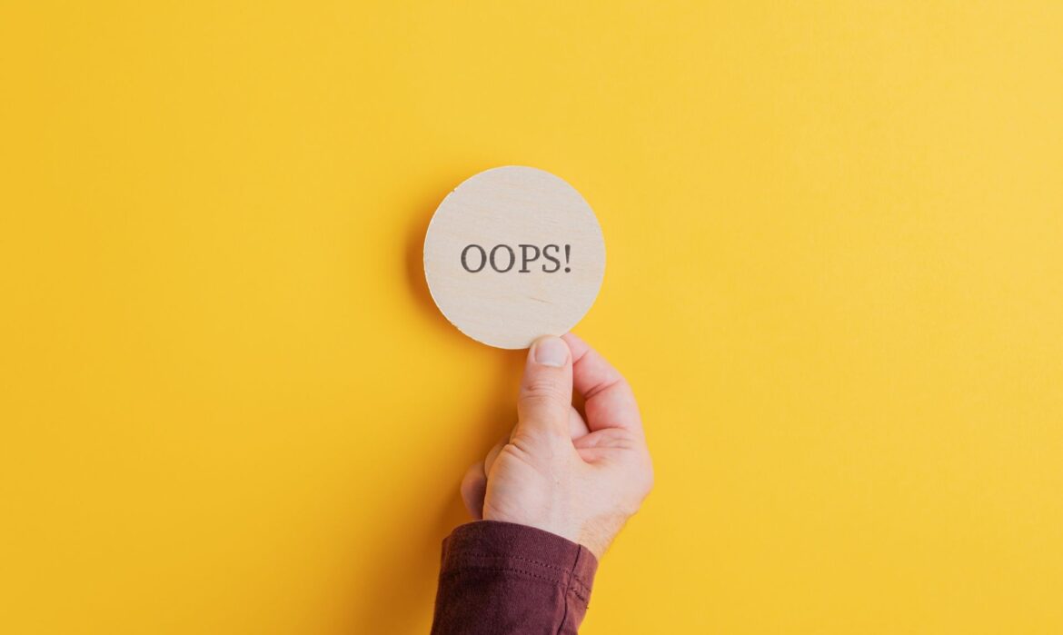 A hand holding an 'Oops' sign on a wooden cut circle, symbolizing overcoming public speaking mistakes with confidence.