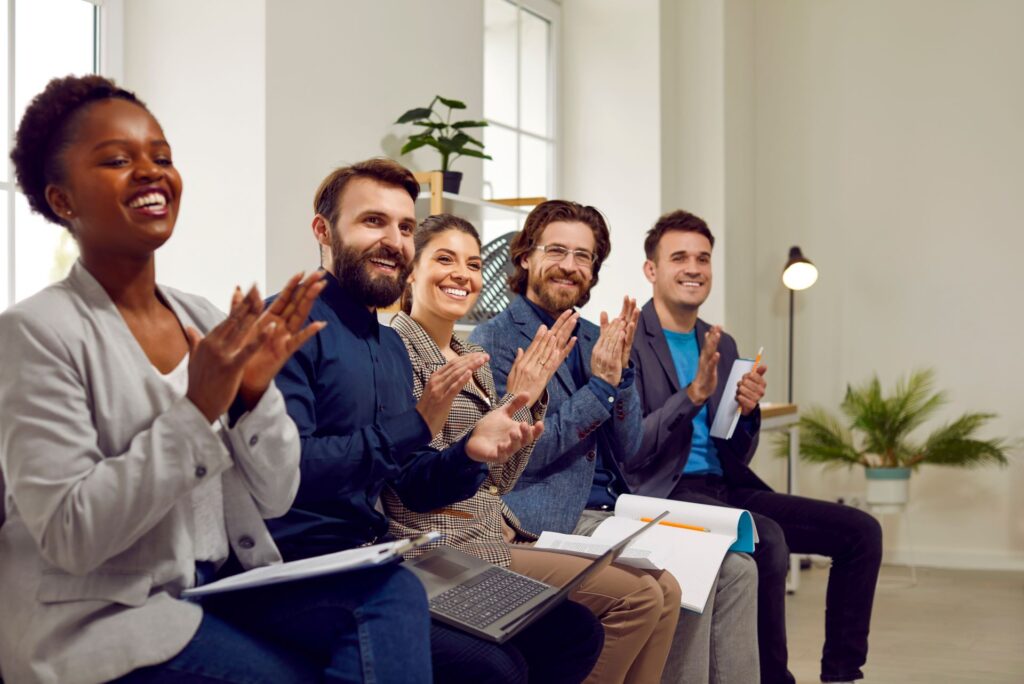 A happy audience clapping enthusiastically, showing the impact of oxytocin in public speaking—building trust, engagement, and emotional connection.